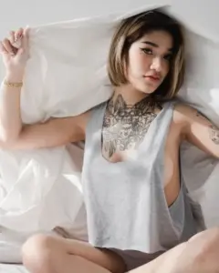 mint_kullanan เสื้อสีเทานั่งบนเตียง